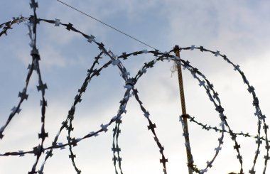 Gökyüzü arka planda duvarda metalik dikenli tel