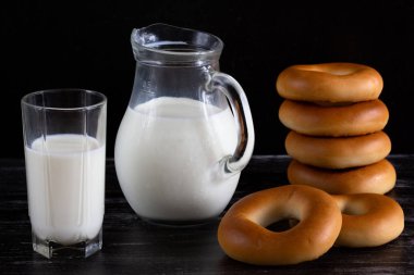 Siyah arka plan üzerinde sürahi ve simit yığını süt