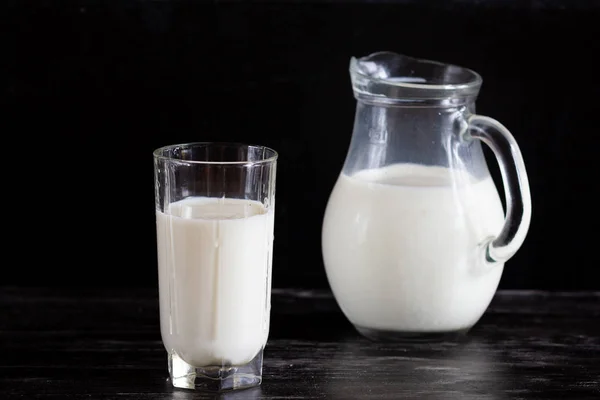 Молоко в стеклянном кувшине на черном фоне — стоковое фото
