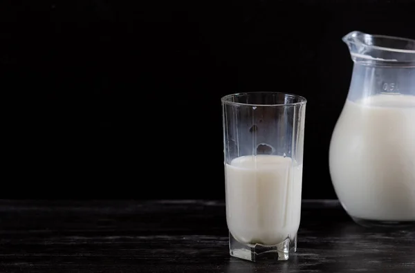 Milk in glass jug on the black background