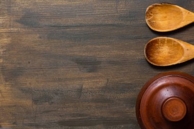 Kopya alanı ile ahşap arka plan üzerinde kil tencere ve ahşap kaşık üst görünümü