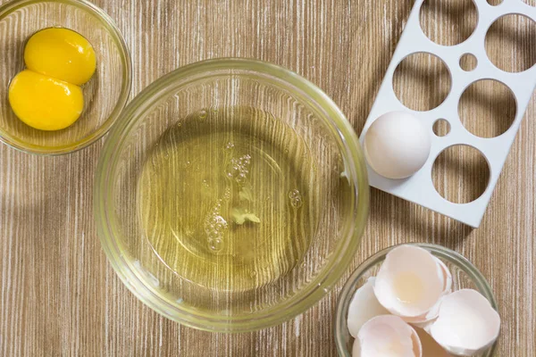 Separated raw chicken yolk and whites on wooden table — Stock Photo, Image