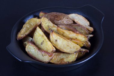 Siyah arka planda siyah tabakta kızartılmış patatesleri kapat.