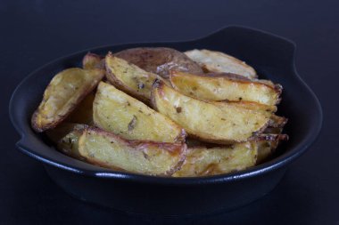 Siyah arka planda siyah tabakta kızartılmış patatesleri kapat.