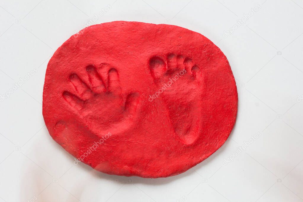 Hand and foot print of child made on red dry doug