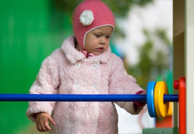 Küçük kız dışarıda tahta oyuncak tezgahıyla oynuyor.