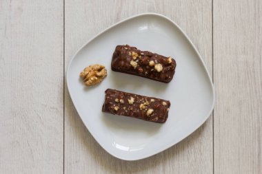 Ceviz kaplı iki çikolatanın üst görüntüsü ve beyaz arka planda beyaz tabakta doluyor.