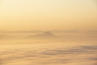 Sabah erken renkli sis aracılığıyla görünür siluetleri ile dağ silsilesi.