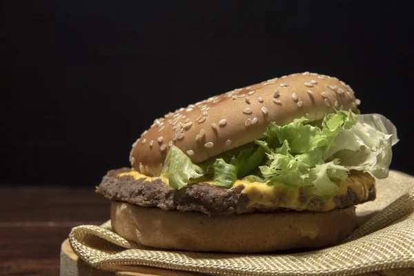 Izgara et ve peynir Burger ahşap masa ve siyah arka plan üzerinde yakın çekim.