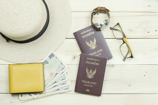 Tayland pasaportu, şapka, Gözlük, saat, sarı cüzdan ve nakit. Seyahat için hazırlanıyor. Ahşap arka plan üzerinde.