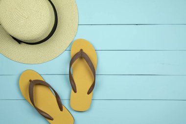 Hasır şapka ve ışık yeşil ahşap arka plan üzerinde flip flop.