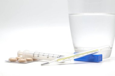 Termometre, hap ve beyaz zemin üzerine su.