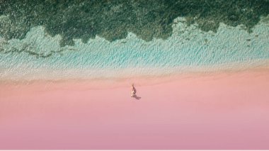 Pink Beach with lady in had lying on the sand. Lombok. Indonesia. clipart
