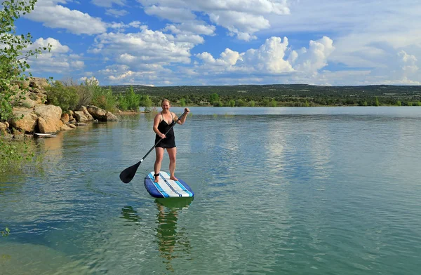 woman on a stand up paddleboard on a lake at dusk, Utah, USA