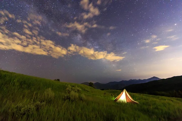 camp tent on green grass under starry sky