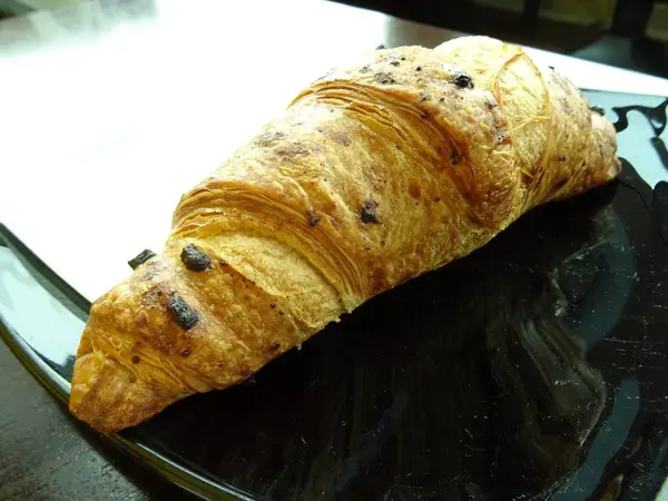 Croissant Einem Schwarzen Teller — Stockfoto