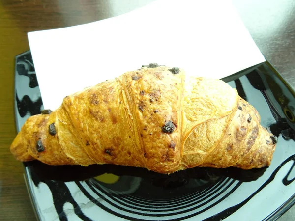Croissant Einem Schwarzen Teller — Stockfoto