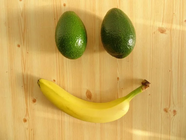 Rosto Sorridente Feito Dois Abacates Uma Banana Mesa Madeira — Fotografia de Stock