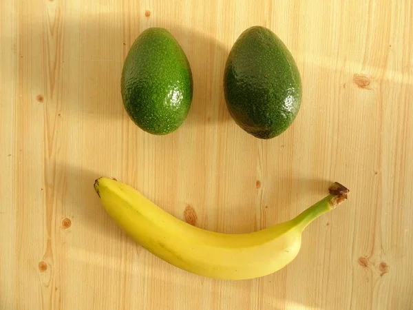 Rosto Sorridente Feito Dois Abacates Uma Banana Mesa Madeira — Fotografia de Stock