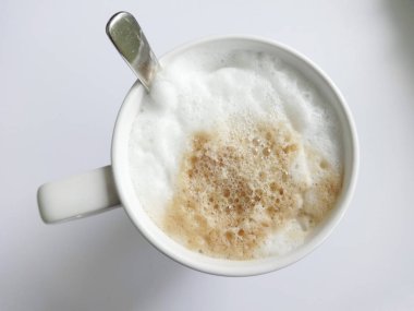 Kapuçino beyaz arka plan üzerinde beyaz bir kupa köpük ile