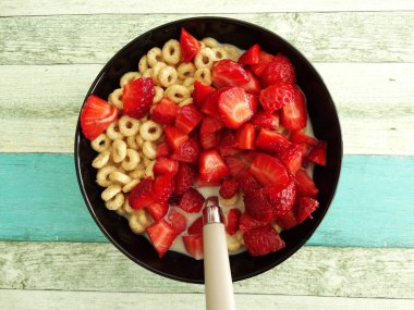 Mısır gevreği Yüzükler bir siyah seramik kase Çilek parçaları ile 