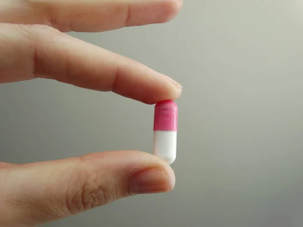 fingers holding medical pill