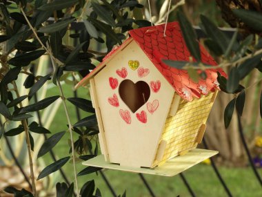 Bir ağaç üzerinde asılı bir kalp deliği ile ahşap kuş evi