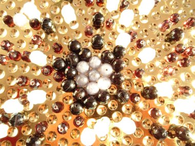 Altın bir plaka üzerinde parlak karışık taş boncuklar