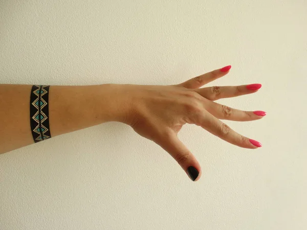 Γυναικείο Χέρι Ροζ Και Μαύρο Βερνίκι Νυχιών Και Ένα Βραχιόλι — Φωτογραφία Αρχείου