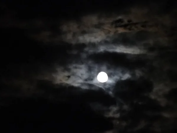 Full Moon among Clouds on Black Sky Background