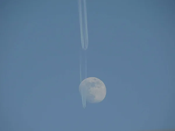 The Moon and Airplane Trails in the Blue Sky