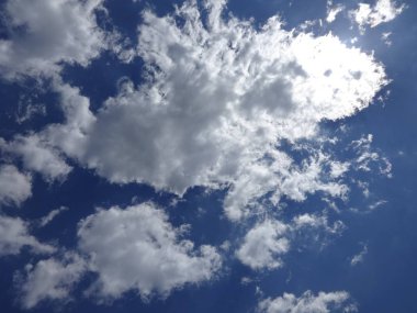 Güneş mavi gökyüzünde beyaz bulutlar arkasında