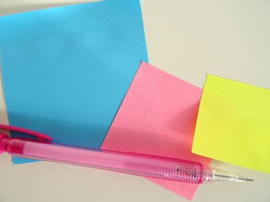 Boş renkli yapışkan notlar ve pembe bir kalem