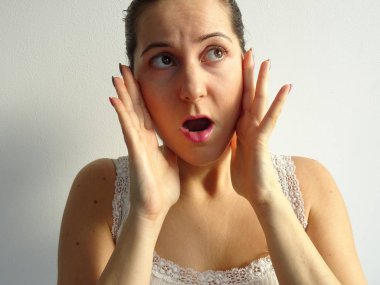 Evde ışık duvara karşı beyaz yelek korkmuş kadın   