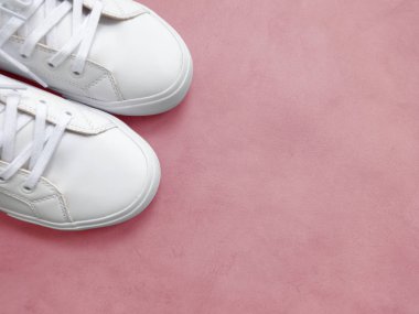 Pembe arka planda beyaz kadın spor ayakkabıları