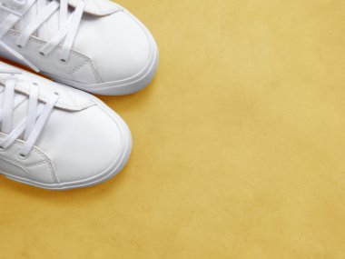 Sarı arka planda beyaz kadın spor ayakkabıları