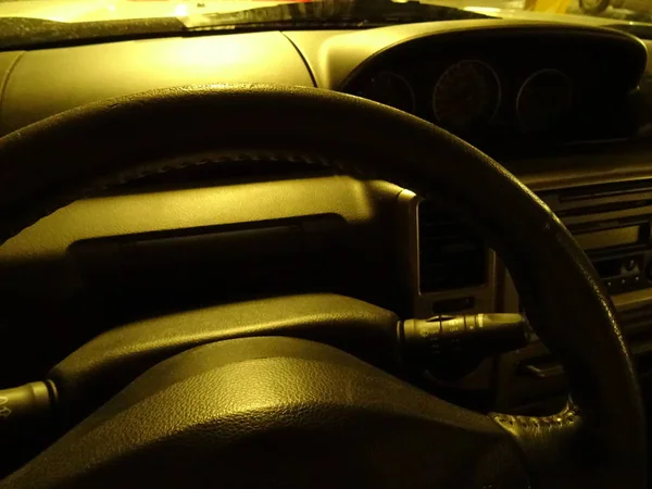 Czarna skórzana kierownica samochodowa pod żółtym światłem — Zdjęcie stockowe
