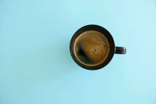 Vista superior de una taza negra de café aislada sobre un fondo azul — Foto de Stock