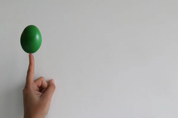 FInger holding a Painted Easter Boiled Egg isolated on a White W