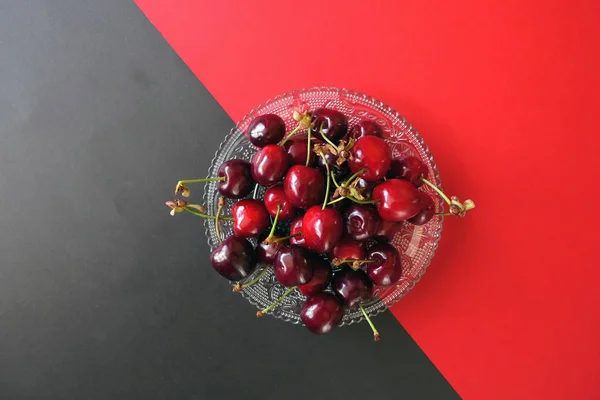 Fresh Dark Red Cherries in a Transparent Plate on a Red and Blac — Stock Photo, Image