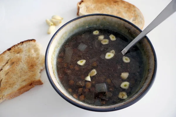 Sopa caseira quente das lentilhas com fatias do alho e do pão isoladas — Fotografia de Stock