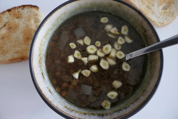 Sopa caseira quente das lentilhas com fatias do alho e do pão isoladas — Fotografia de Stock