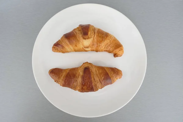 Köstliche französische Croissants und in einem weißen Teller isoliert auf einem g — Stockfoto