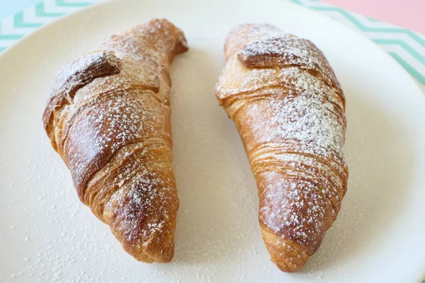 緑の上に隔離された白いプレートの美味しいフランスのクロワッサン — ストック写真