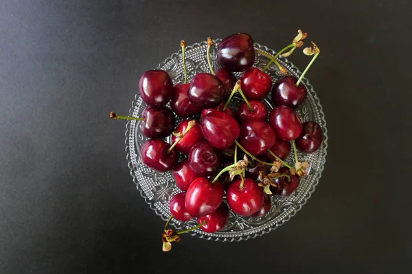 Cerejas vermelhas escuras frescas em uma placa transparente isolada em uma Bla — Fotografia de Stock