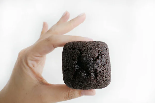 Mano sosteniendo un Brownie de chocolate aislado sobre un fondo blanco —  Fotos de Stock