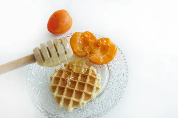 Waffle com mel e damascos isolados em um fundo branco — Fotografia de Stock