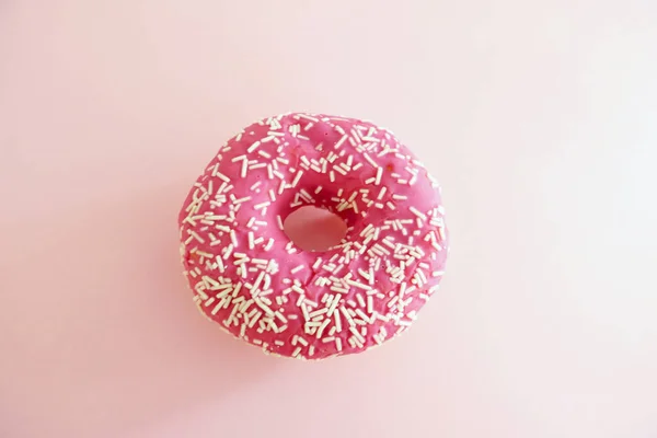 Donut polvilhado rosa suculento isolado em um fundo rosa — Fotografia de Stock