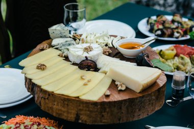 Yuvarlak ahşap tezgahta çeşitli peynir çeşitleri
