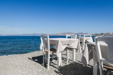 Beyaz Restoran tablolar sahilde yaz - seyahat, tatil ve yaz konsepti. Deniz manzaralı mükemmel bir öğle yemeği